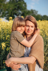 Fototapeta premium Mother with son in rapeseed field