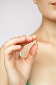 a woman holds a vitamin capsule in her hand. taking vitamins and nutritional supplements for female beauty and health