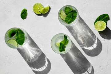 Summer refreshing cocktail Mojito with rum, mint, lime and ice in glass on a white stone background...