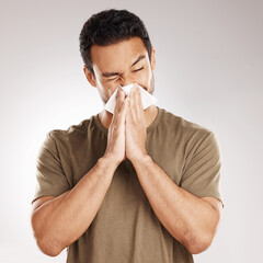 Man sneezing, blowing nose and tissue with virus and health issue against a grey studio background....