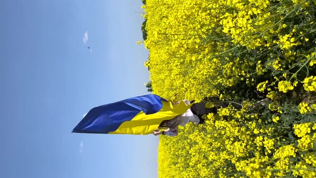 A young girl with a flag of Ukraine is running on a yellow field