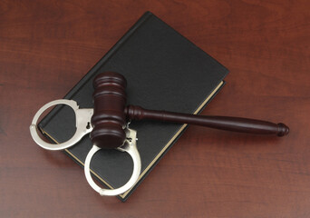Top view of handcuffs with gavel and legal book on table. Laws and crimes concept. 