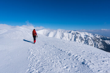 Happy woman relaxing on the top of mountain under blue sky with sunlight at sunny winter day, travel vacation, landscape mountains background.