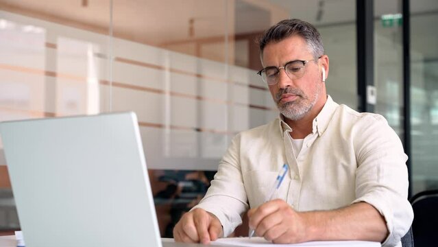 Middle-age Hispanic man using computer remote for business studying, watch online virtual webinar training meeting, video call. Smiling mature Indian or Latin businessman working on laptop in office.