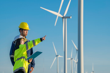 Two engineers working and holding the report at wind turbine farm Power Generator Station on...
