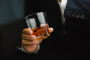 Young man holding whiskey glass in bar or restaurant.