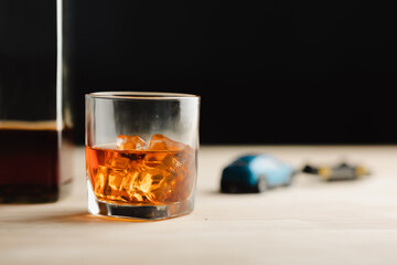 Glass of whiskey with ice on table in counter in bar and car keys