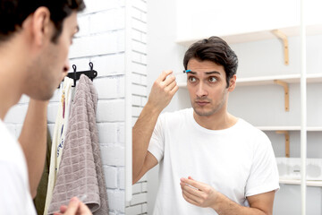 Handsome man doing facial injections himself at home	