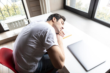 Tired and bored student sleeping on the desk while preparing for exams	