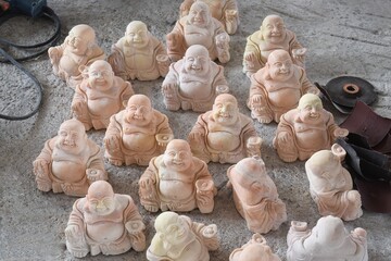 Collection of Laughing Buddha statuettes being polished near Ha Long Bay, Vietnam - obrazy, fototapety, plakaty