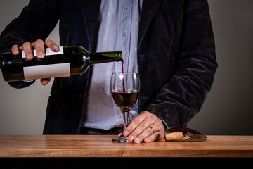Hombre elegante sirviendo una copa de vino tinto