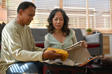 Preparing luggage for going on vacation during retirement with senior aged couple.