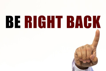 Be right back text on white wall background with businessman's finger point at the message with empty space. This message can be used as business concept about be right back.