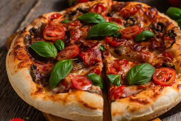 Appetizing pizza. Pizza with ham, mushrooms and tomatoes on a wooden background
