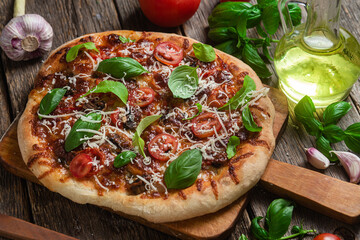 Appetizing pizza. Pizza with ham, mushrooms and tomatoes on a wooden background