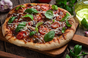 Appetizing pizza. Pizza with ham, mushrooms and tomatoes on a wooden background
