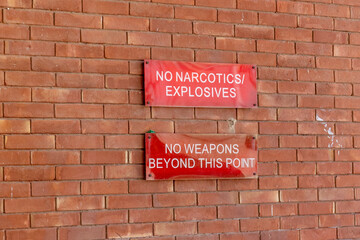 no narcotics explosives no weapons beyond this point signs on a brick wall