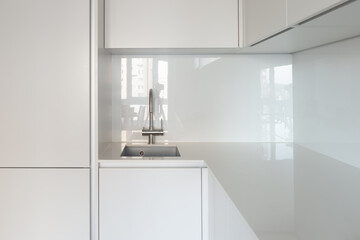 Close-up of the sink and work area in the kitchen with an ultra-thin countertop and glass backsplash
