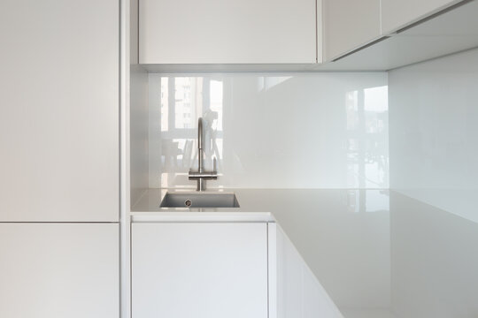 Close-up of the sink and work area in the kitchen with an ultra-thin countertop and glass backsplash