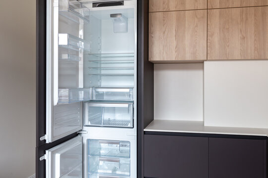 Opened built-in fridge in a kitchen with brown fronts 