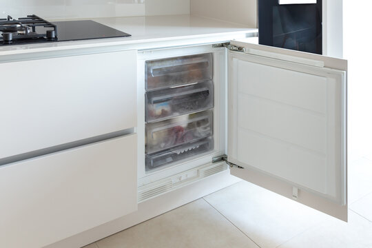 Opened build-in freezer in a light bright kitchen