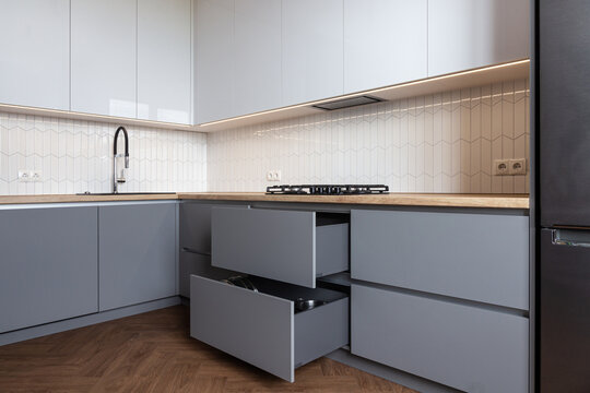 Opened kitchen drawers in a grey white kitchen 
