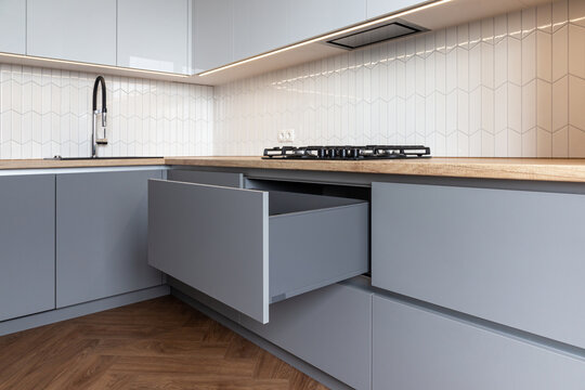 Opened kitchen drawer in a grey white kitchen 