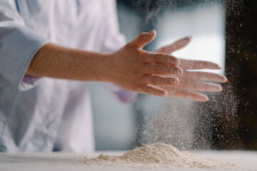 An experienced chef applies flour to his hands before making bread in a bakery prepares pastries in a professional kitchen