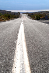 empty highway leading through desert landscape towards dry salt lake