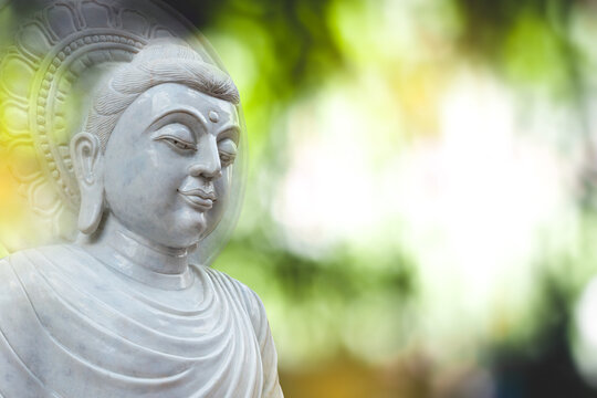 White jade Buddha statue on natural bokeh blurred background, buddha face