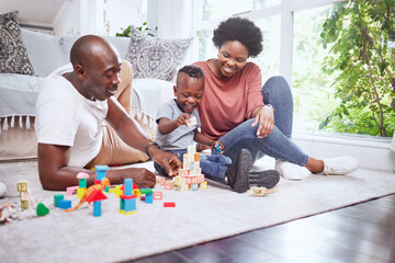 Toys, building blocks and black family playing on a living room floor happy, love and bonding in...