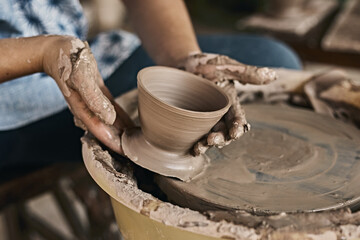 Fototapeta na wymiar Hands of craftsman artist working on pottery wheel.