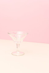 Small crystal glass in front of pink background. Minimal concept with copy space.