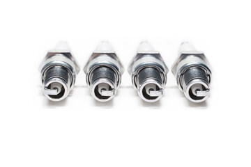 Four spark plugs on a white