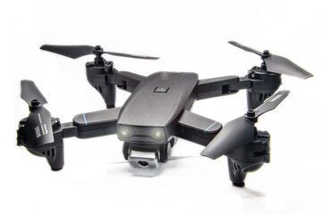 A small dark gray quadrocopter on a white background with glowing headlights and glare	
