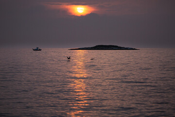 Sonnenuntergang mit Insel und Boot am Mittelmeer