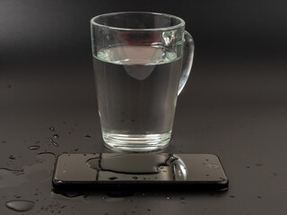Water has been spilled on the Smartphone. The smartphone fell into the water. Wet smartphone on a black background.