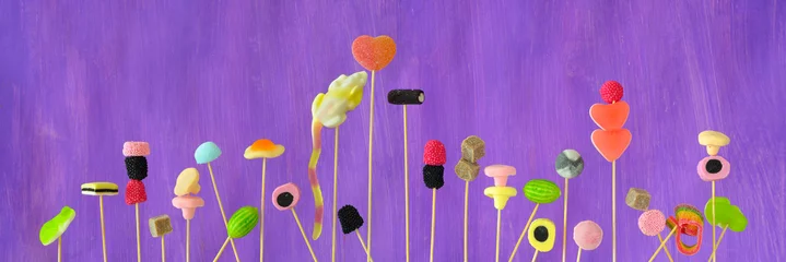 Fotobehang miscellaneous candy and sweets, close up, panoramic format, purple background © Kirsten Hinte