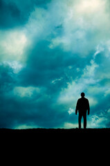man standing on the edge of a cliff, cloudy dramatic sky above