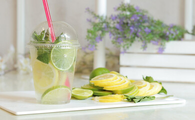 Homemade mojito or lemonade. A plastic cup with a refreshing drink in a bright kitchen
