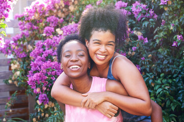 Two best friends hugging piggyback outside in summer, pink flowers friendship