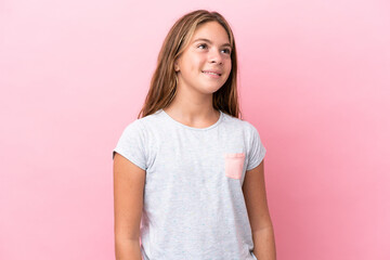 Little caucasian girl isolated on pink background thinking an idea while looking up