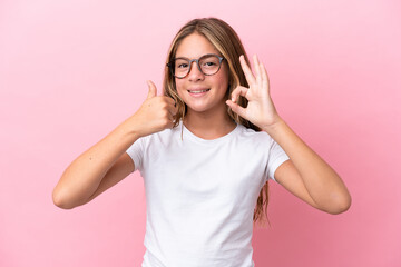 Little caucasian girl isolated on pink background With glasses and doing OK sign