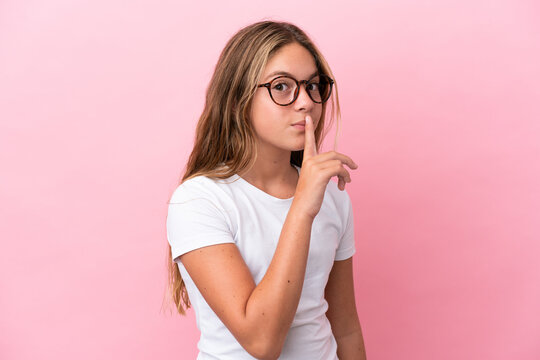 Little caucasian girl isolated on pink background With glasses and doing silence gesture