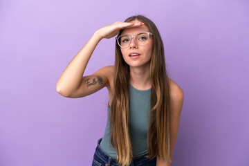 Young Lithuanian woman isolated on purple background looking far away with hand to look something
