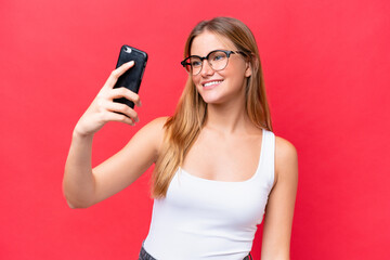 Young beautiful woman isolated on red background making a selfie