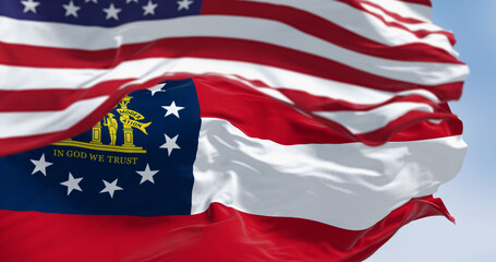 The flags of Georgia and United States waving in the wind on a clear day