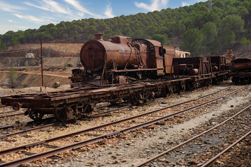 Fototapeta na wymiar Steam engine and freight cars rusting on tracks outside. Train at Rio Tinto