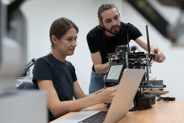 Teamwork of engineer inspecting quality of compact desktop robotic arm for manufacturing lines in workshop. Smart automation tasks concept