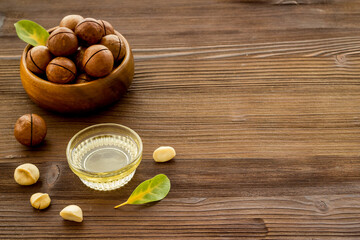 Bowl of of macadamia nuts oil with raw nuts. Natural oil for cosmetic or cooking